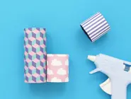 Two different sized wrapped toilet roll tubes glued side by side on a blue background.